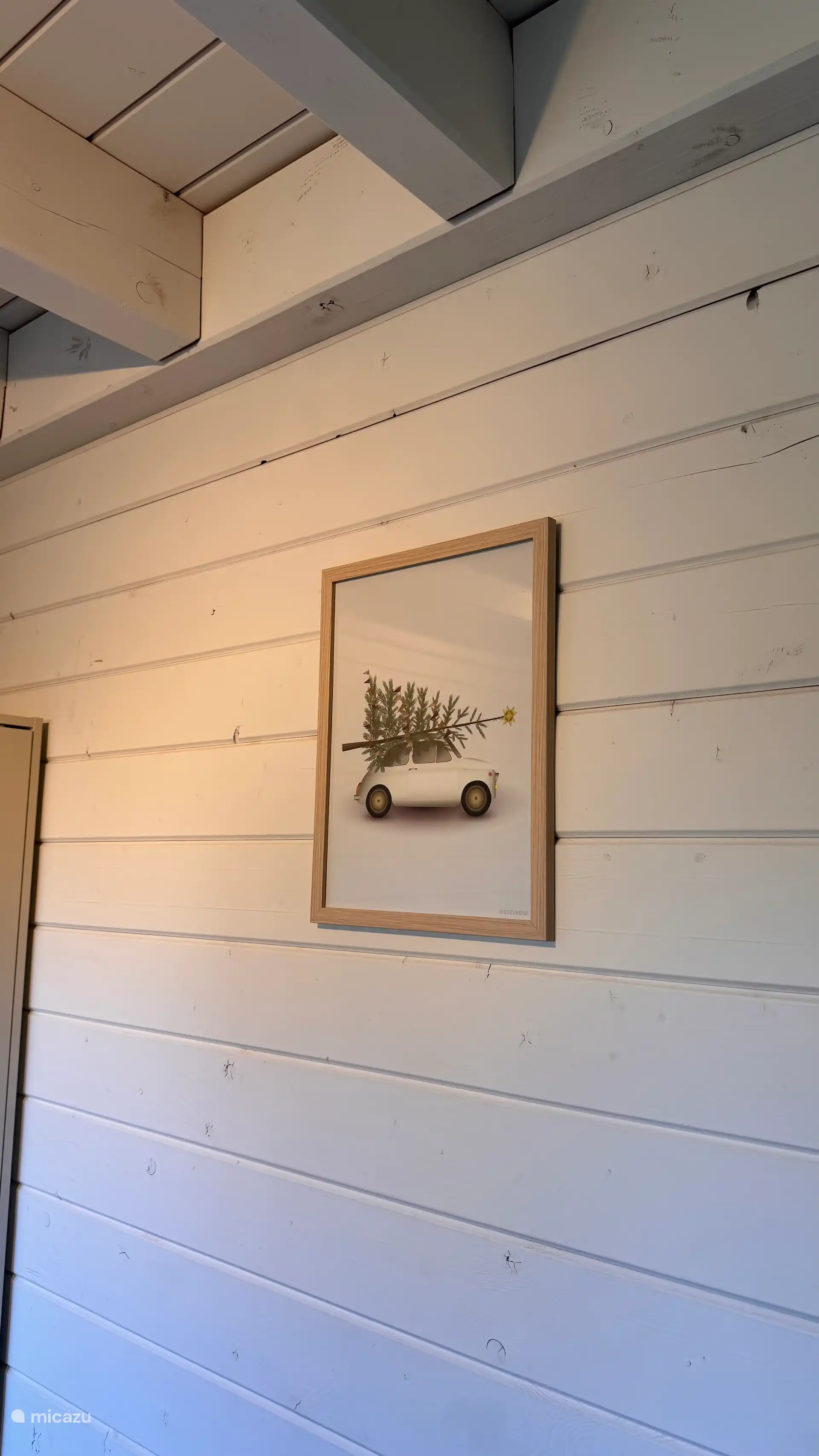 Stijlvolle wanddecoratie met natuurlijke tinten en een speels detail. De houten lijst en lichte wand zorgen voor een rustige, warme uitstraling in het interieur.