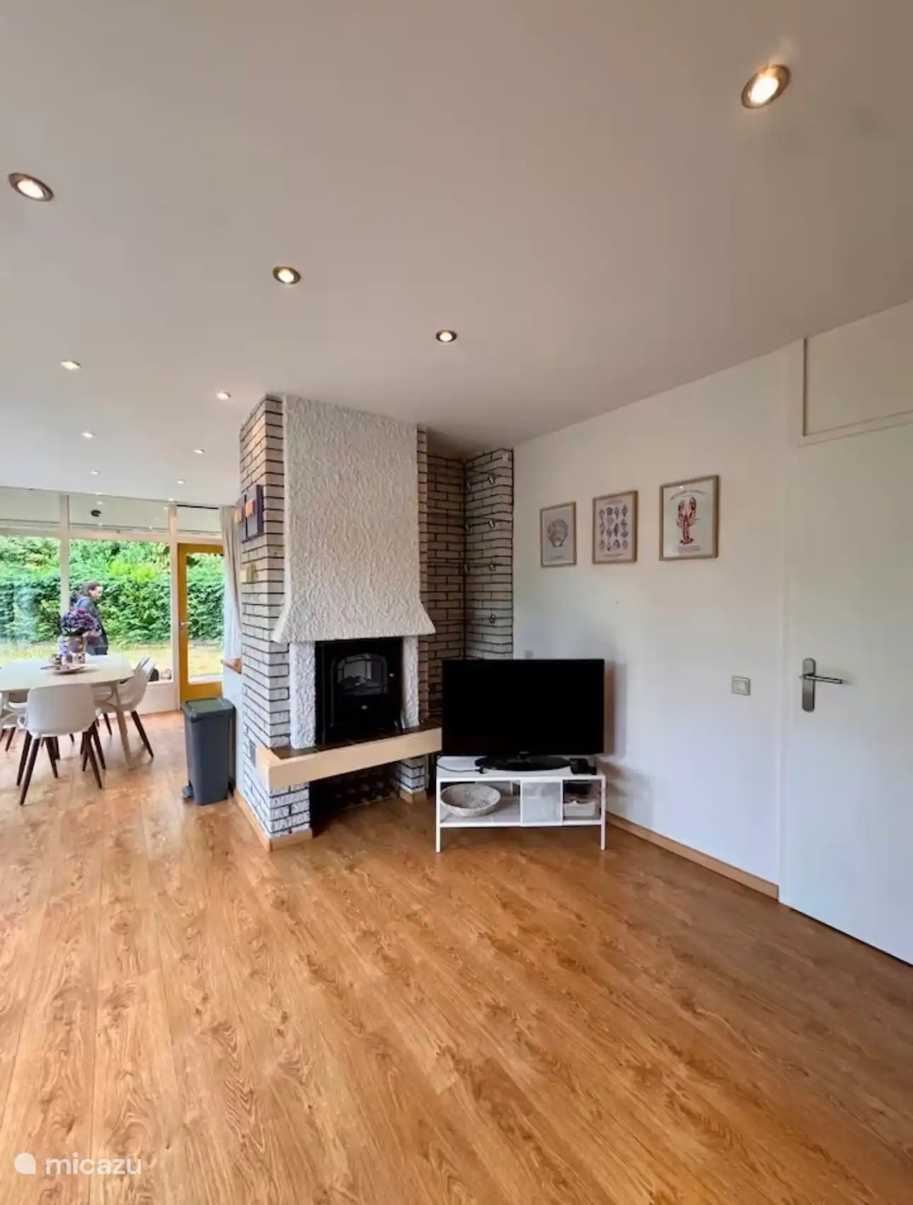 Sfeervolle leefruimte met karaktervolle open haard en warme houtvloer. De open indeling en het uitzicht op de tuin zorgen voor een lichte en ontspannen vakantiesfeer.