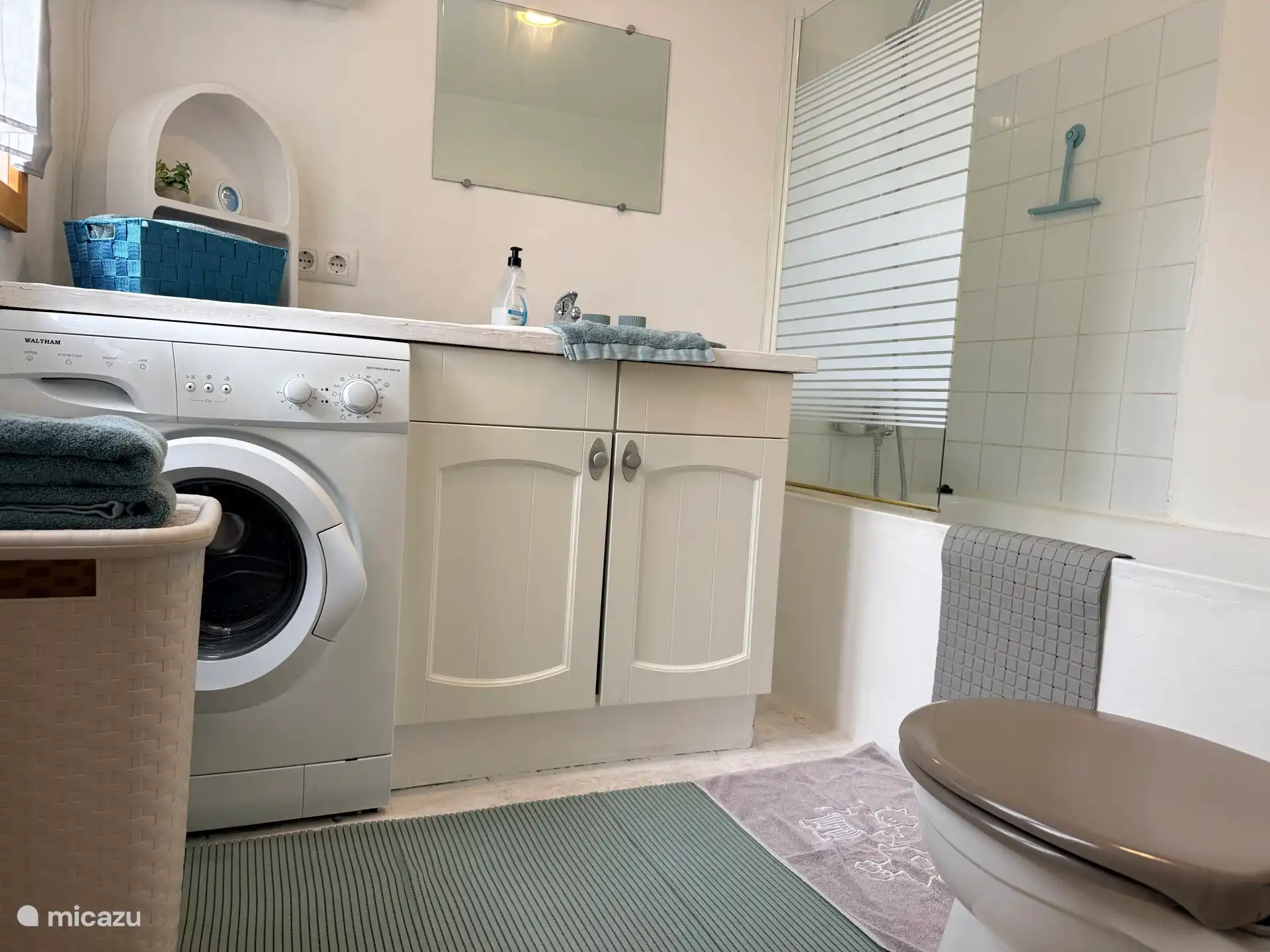 Badkamer met ligbad en douche en ook wasmachine