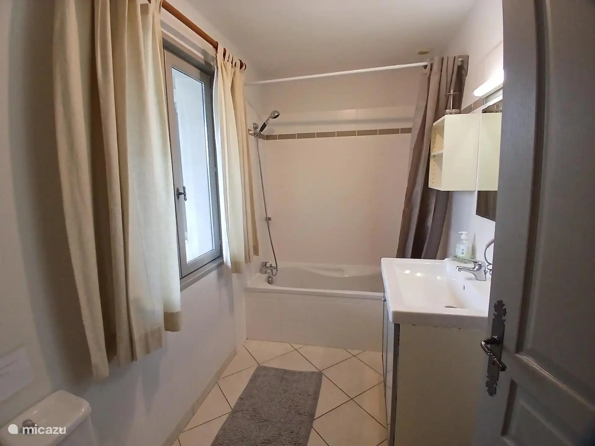 En-suite badkamer met bad, douche, toilet en wastafel