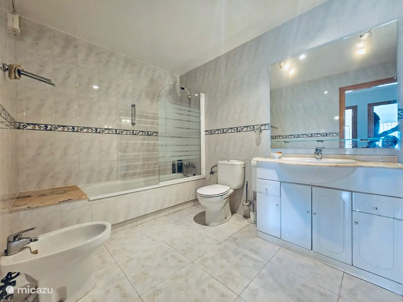 Badkamer voorzien van bad met douche, toilet, bidet, wastafelmeubel. 