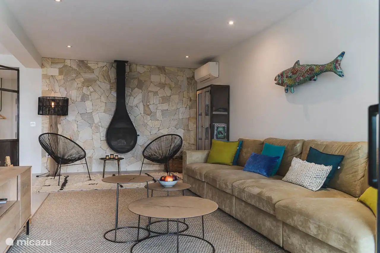 Salon avec canapés, TV, climatisation, accès terrasse.