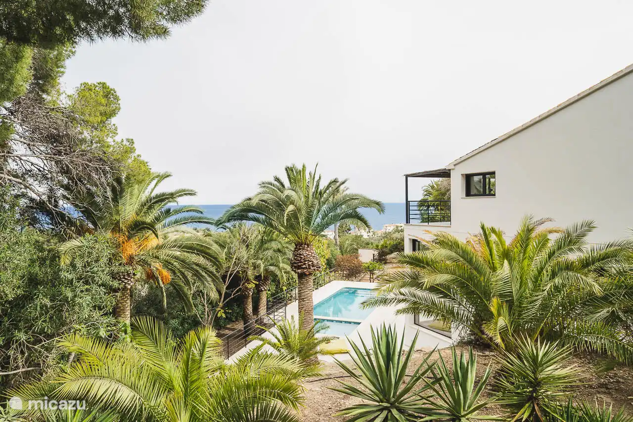 Piscine entourée d'une terrasse avec chaises longues jardin arboré, vue sur la mer, salon extérieur, salle à manger, barbecue.