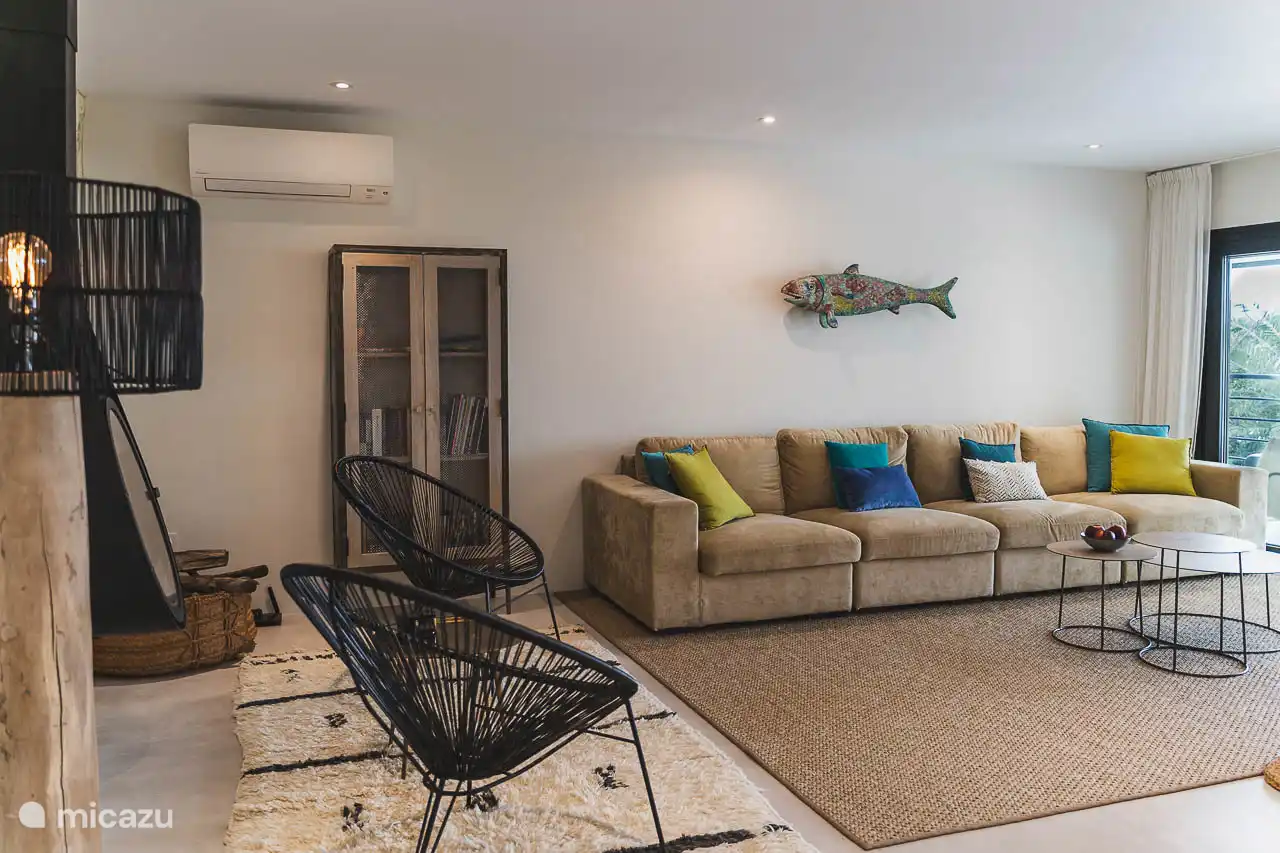 Salon avec canapés, TV, climatisation, accès terrasse.