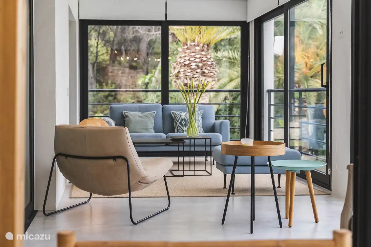 Salon avec canapés, TV, climatisation, accès terrasse.