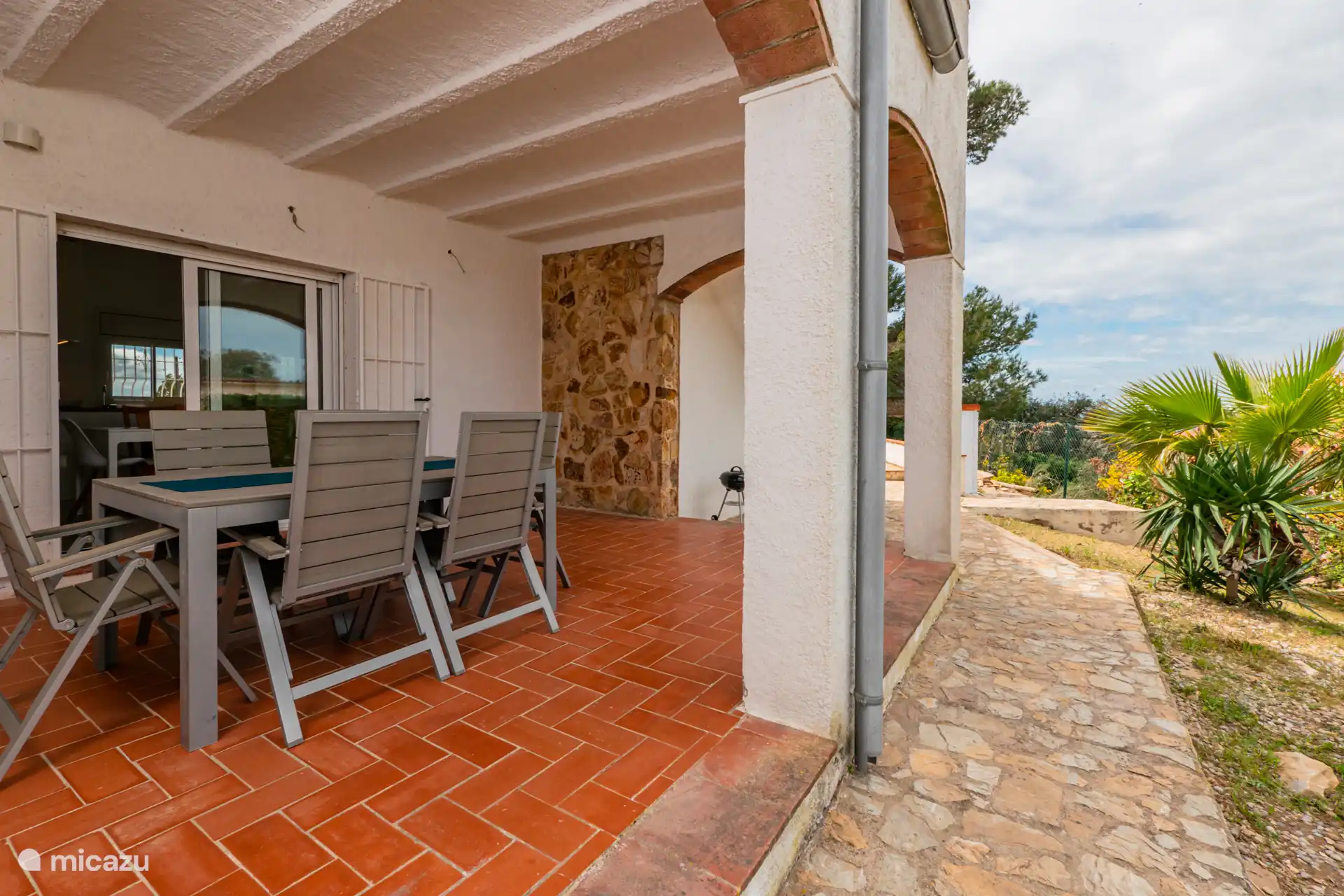 Buiten een overdekt terras dat naar het zwembad leidt