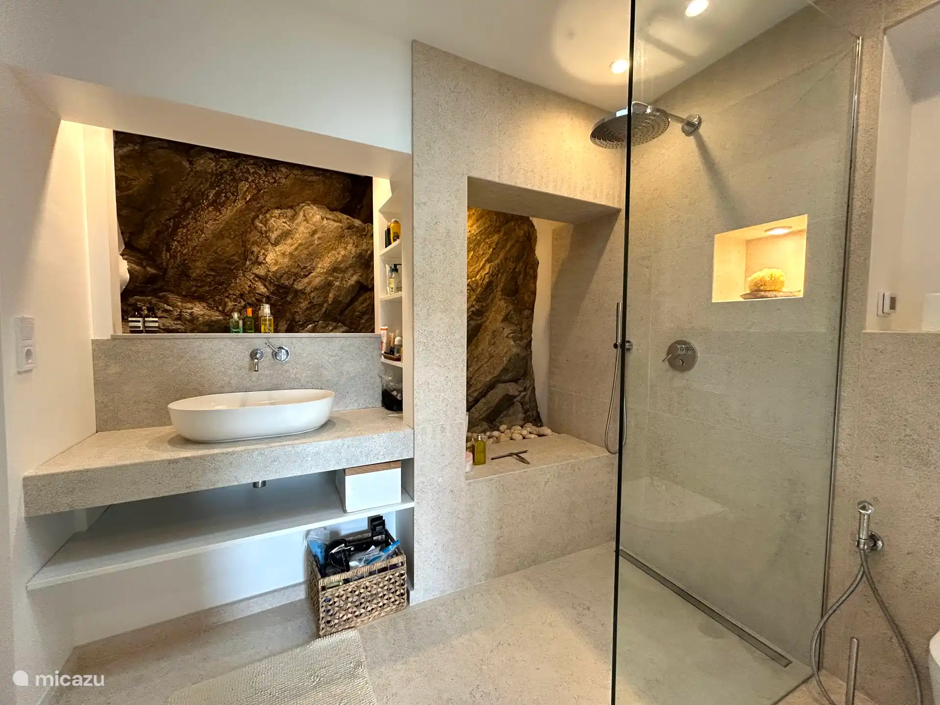 Badezimmer mit Badewanne, Regendusche und einer echten Steinwand