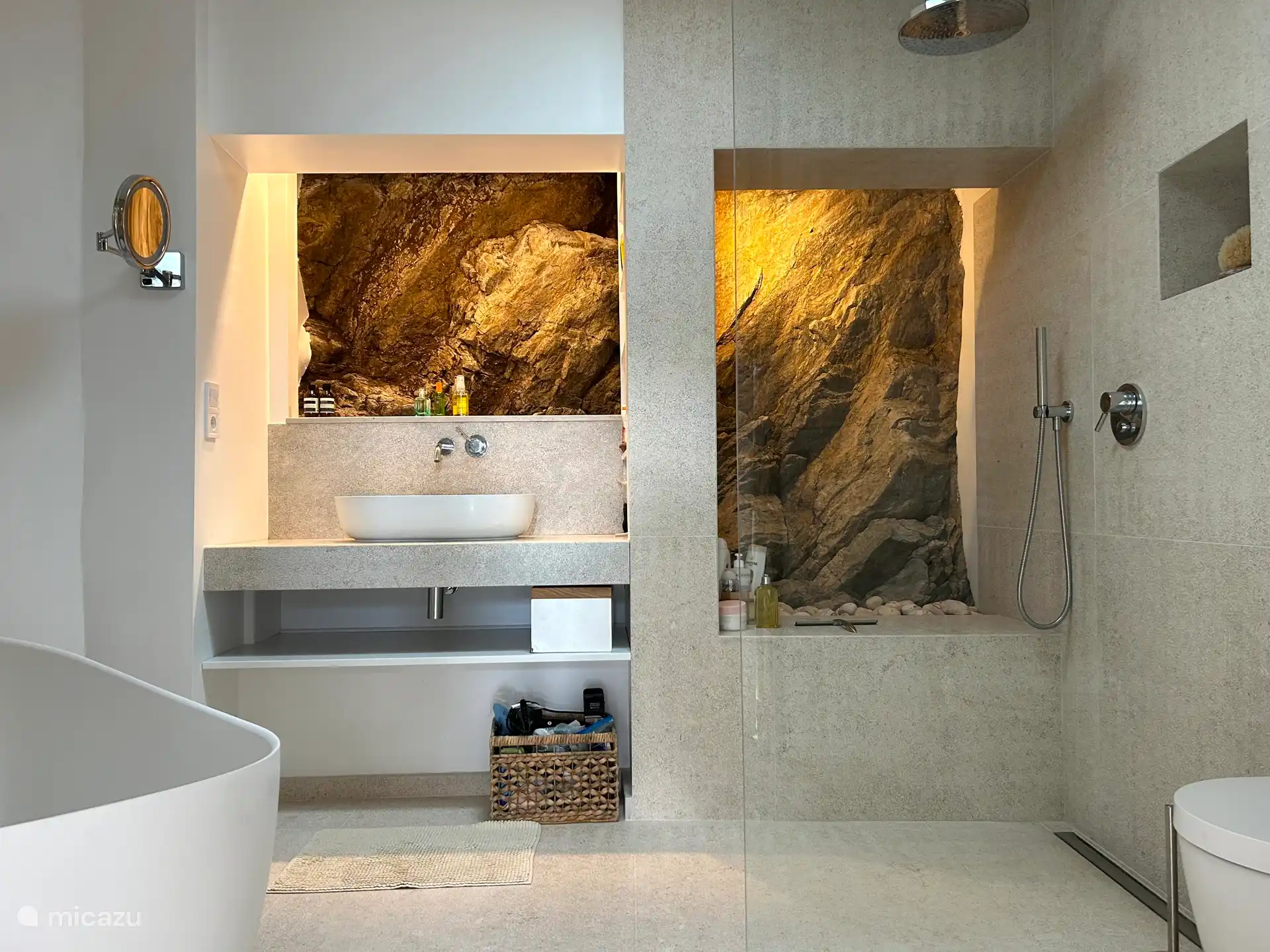 Badezimmer mit Badewanne, Regendusche und einer echten Steinwand
