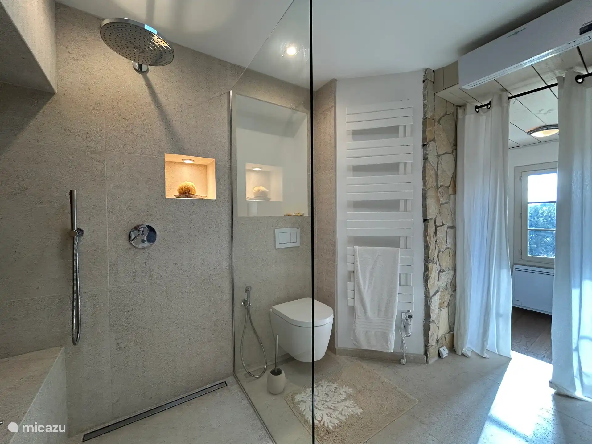 Badezimmer mit Badewanne, Regendusche und einer echten Steinwand
