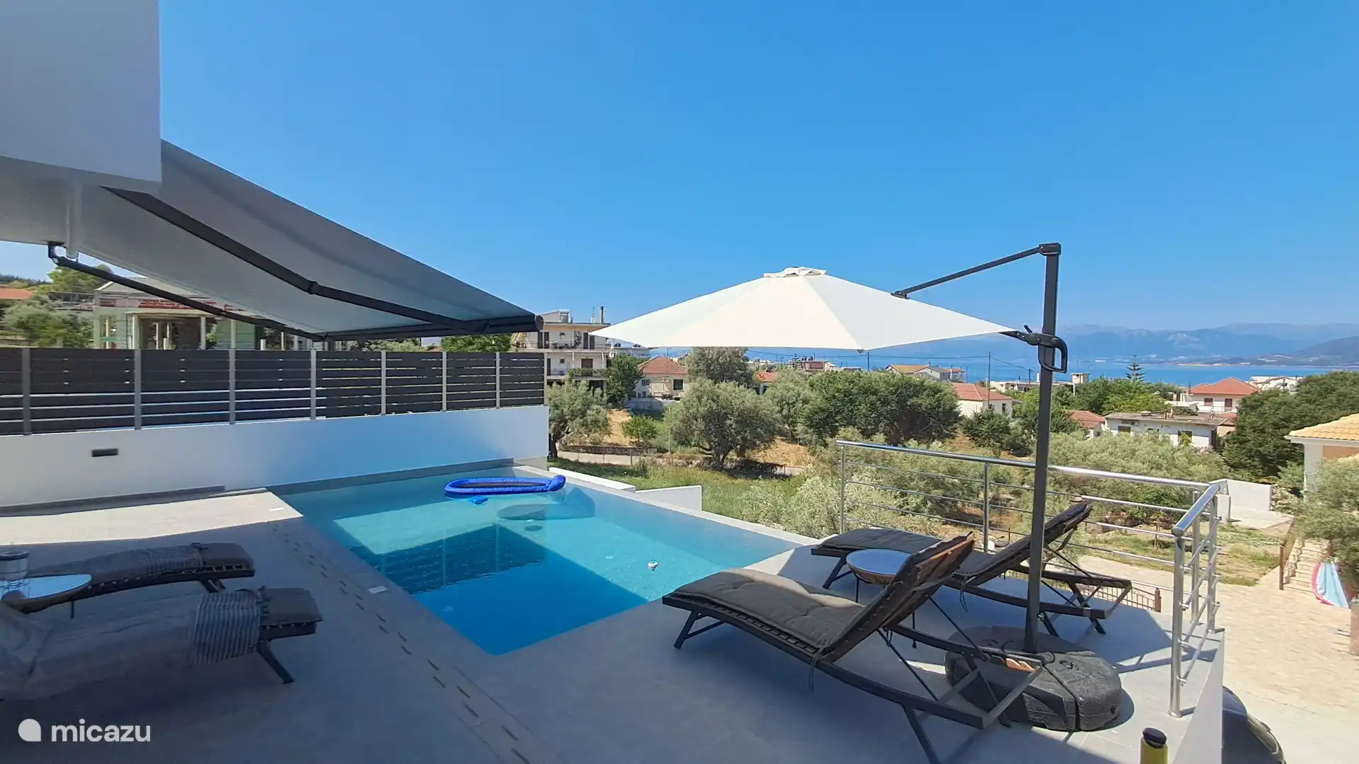 Pool area with sunbeds and the fantastic view of the town and the Ionian Sea 
