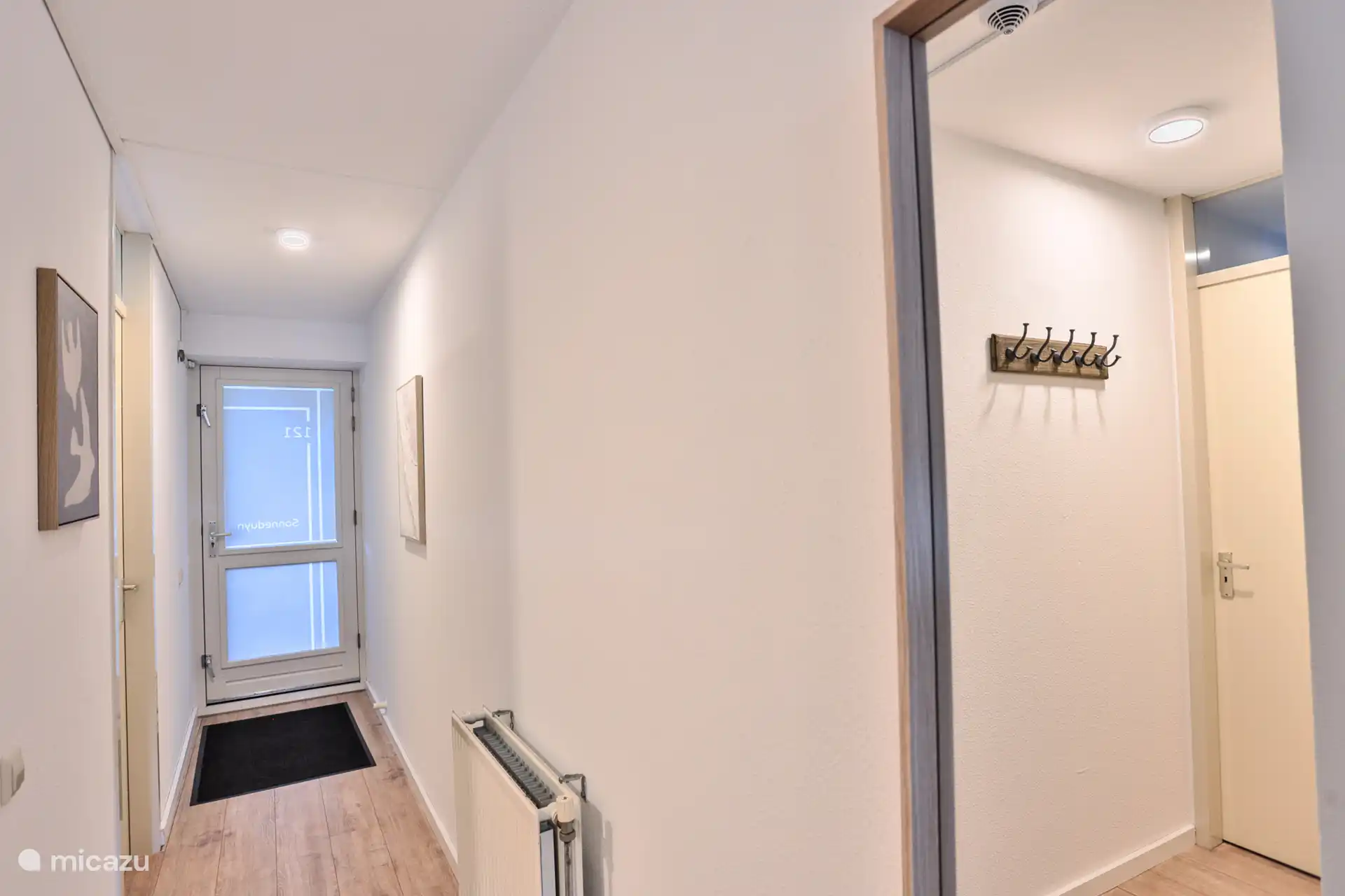 Puerta principal y pasillo con perchero. Hay armarios empotrados en el vestíbulo.