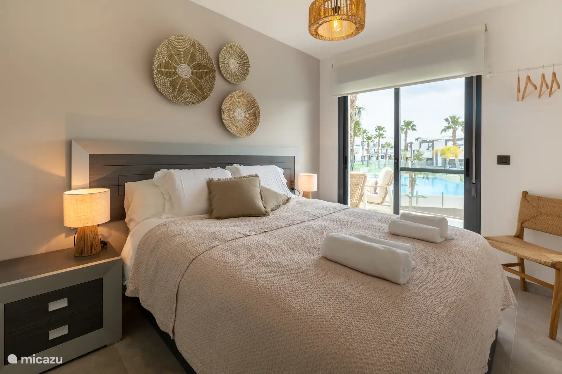 La première chambre a des portes coulissantes donnant sur le balcon et offre une belle vue sur la piscine et les palmiers, vous réveillant chaque matin avec une ambiance relaxante de vacances.