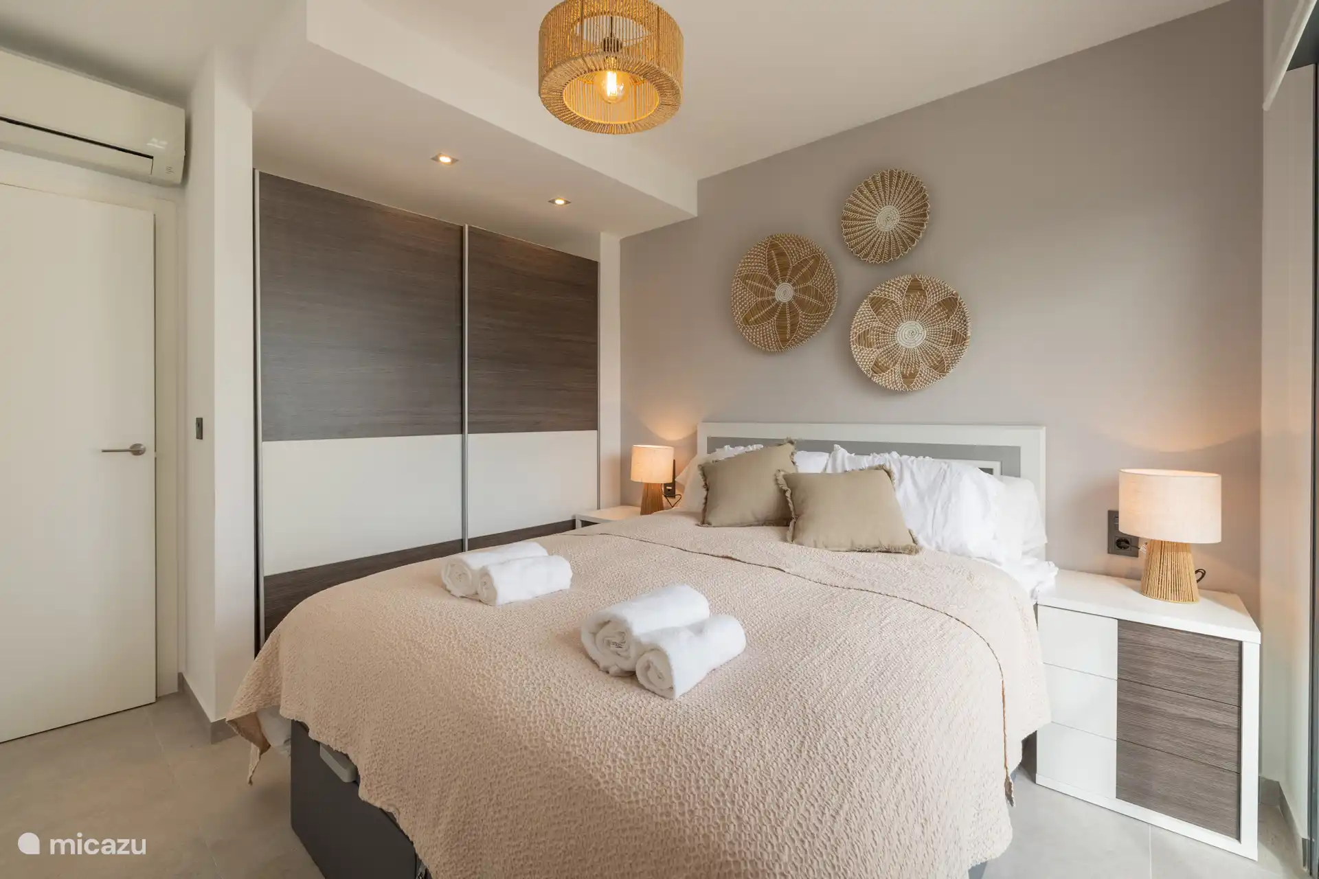 La chambre deux possède également des portes coulissantes donnant sur le balcon donnant sur la piscine et les palmiers, ce qui apporte beaucoup de lumière et une ambiance d’espace.