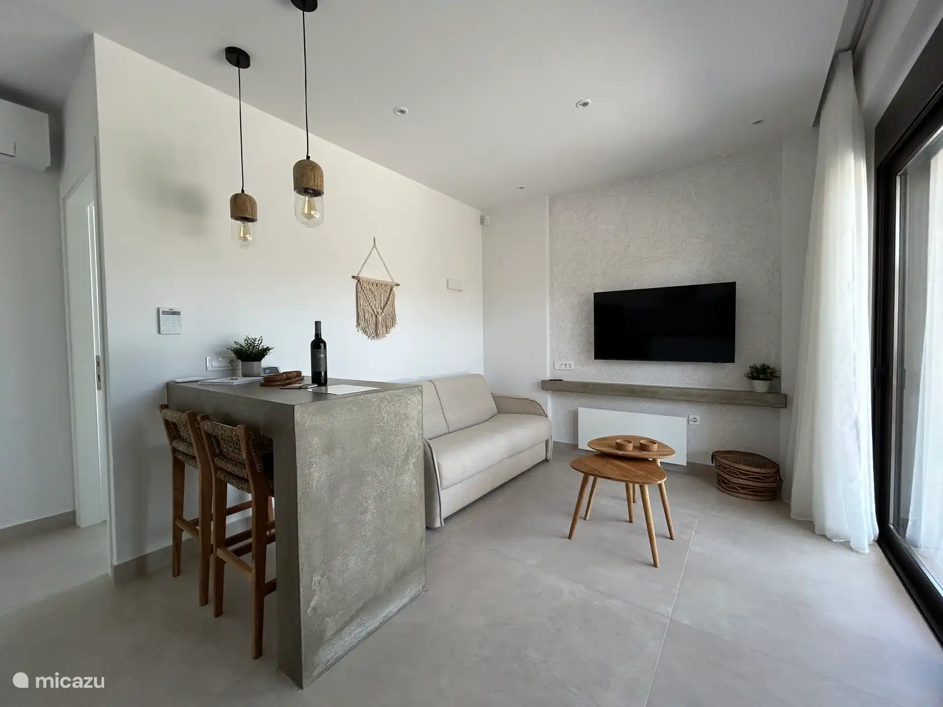 Das Wohnzimmer mit bequemem Sofa, Fernseher und so viel natürlichem Licht 