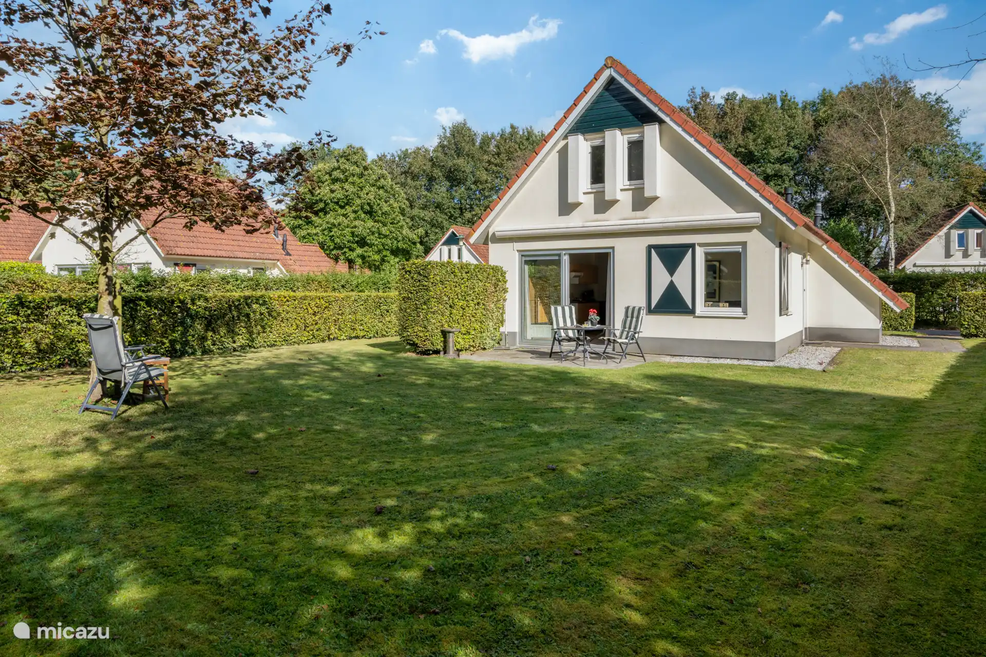 Ruime tuin met gazon en terras met tuinmeubilair