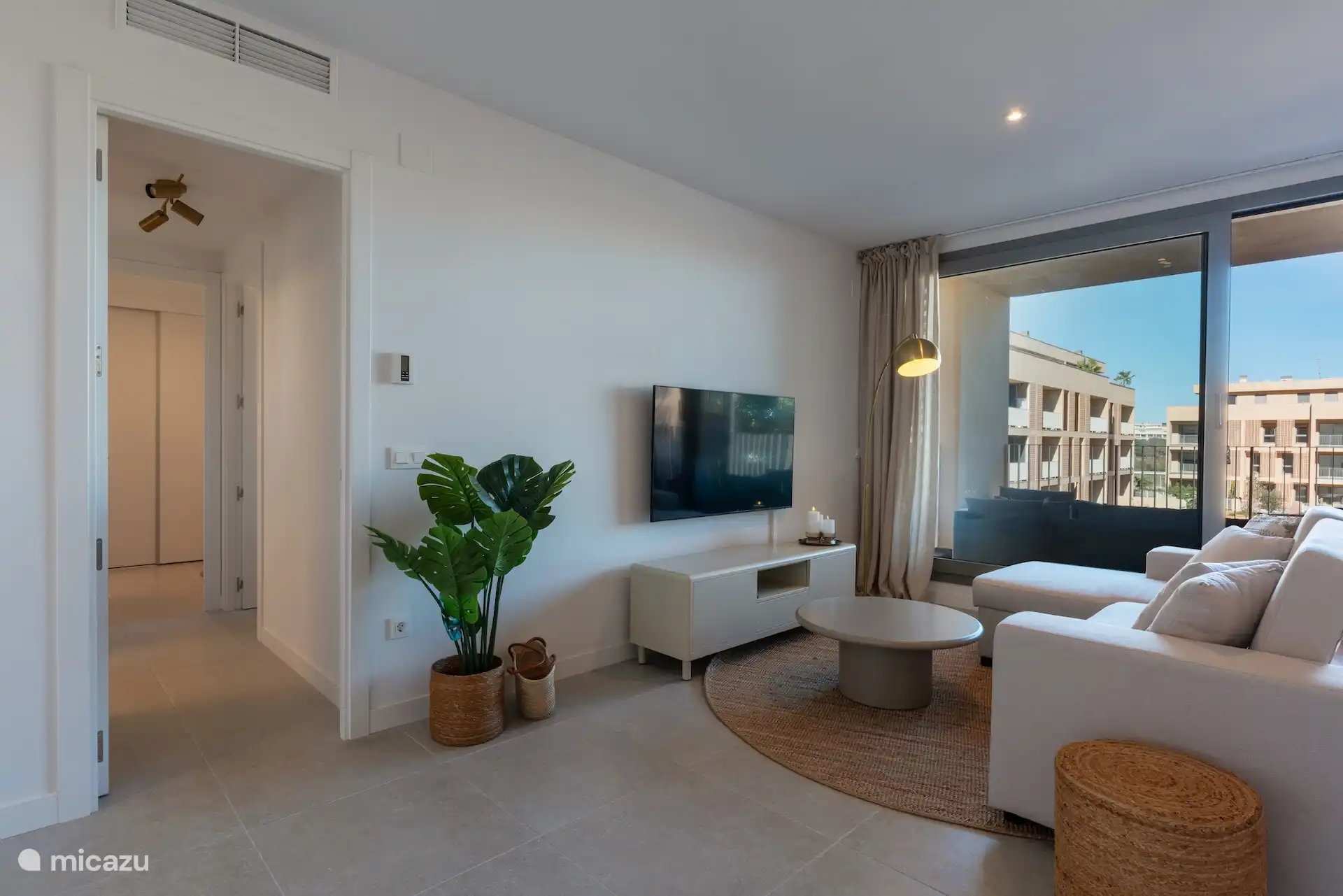 Living room with flat screen TV and view of hallway to bedrooms and bathrooms