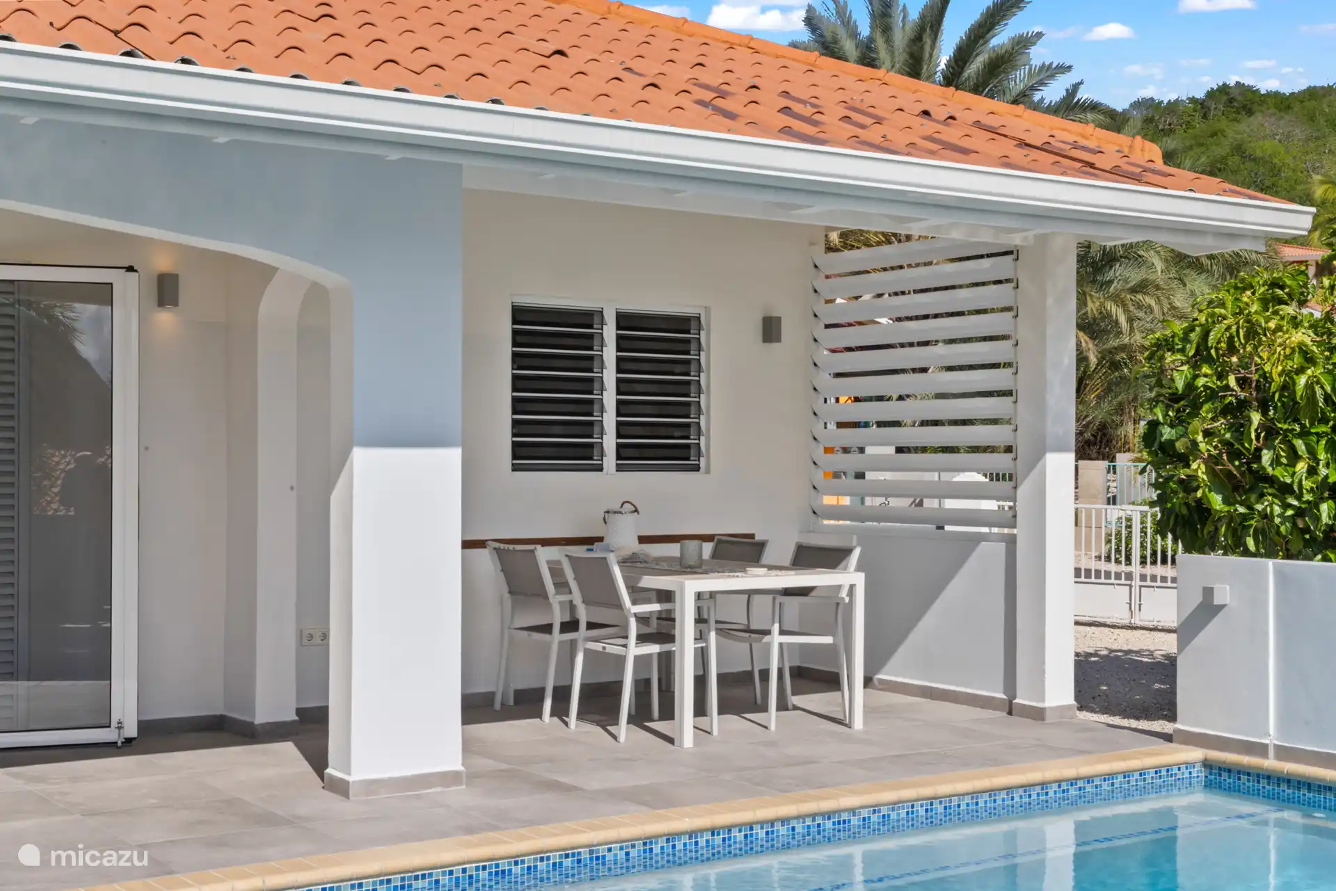 De overdekte buitenruimte met een fijne eethoek. Door de shutters te voorzien van een heerlijke bries. 