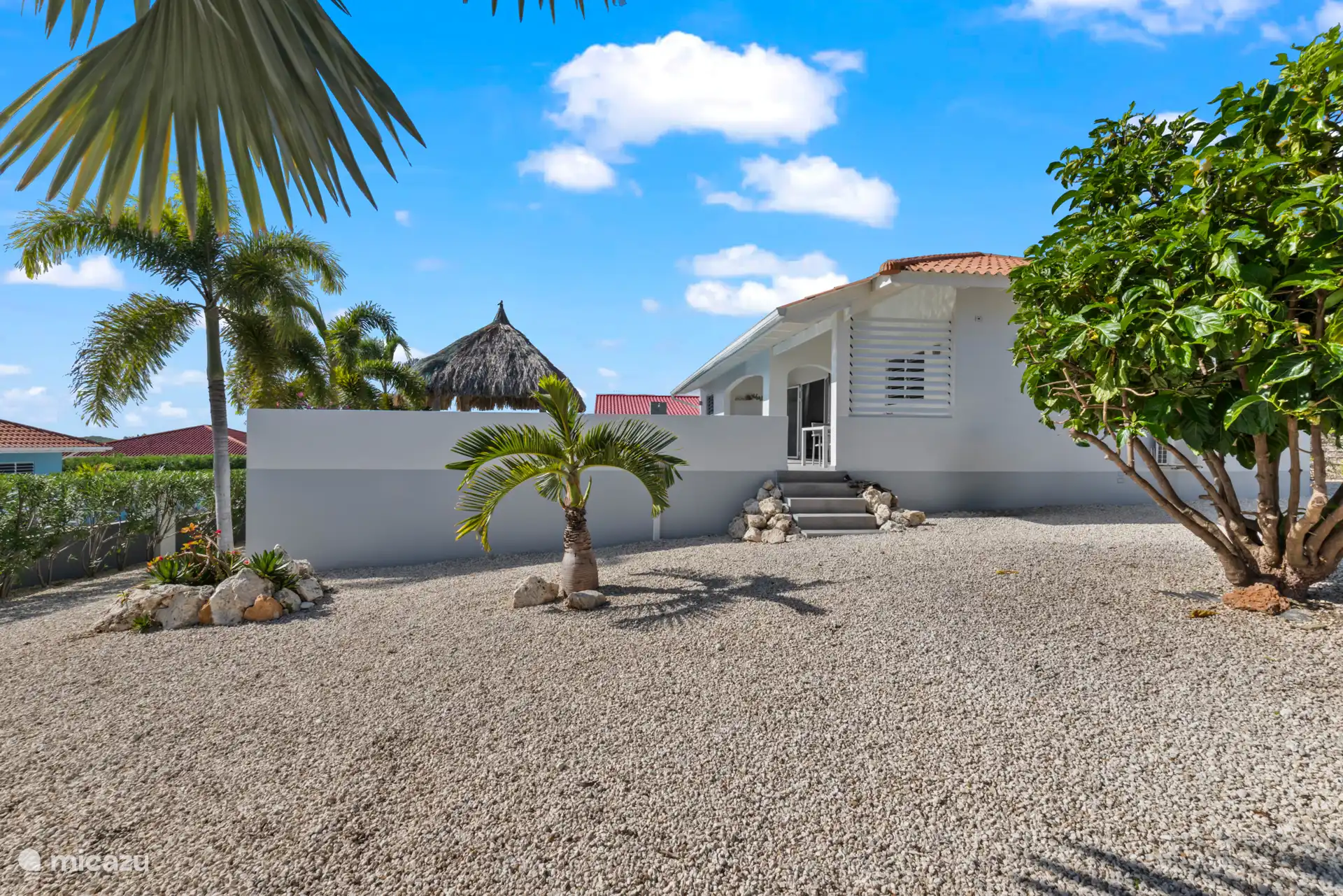 Het huis gezien vanuit de omheinde tuin met het trapje richting de porche. 