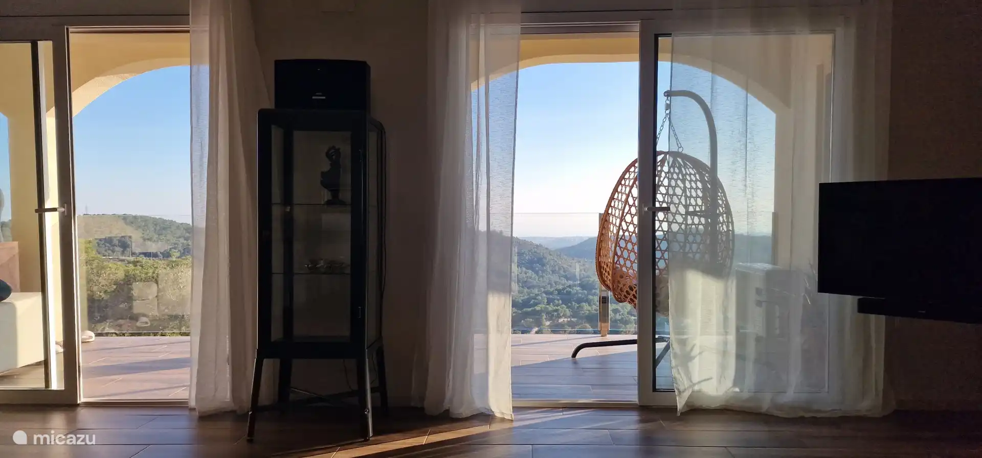 Uitzicht van bank in woonkamer naar balkon en verder...