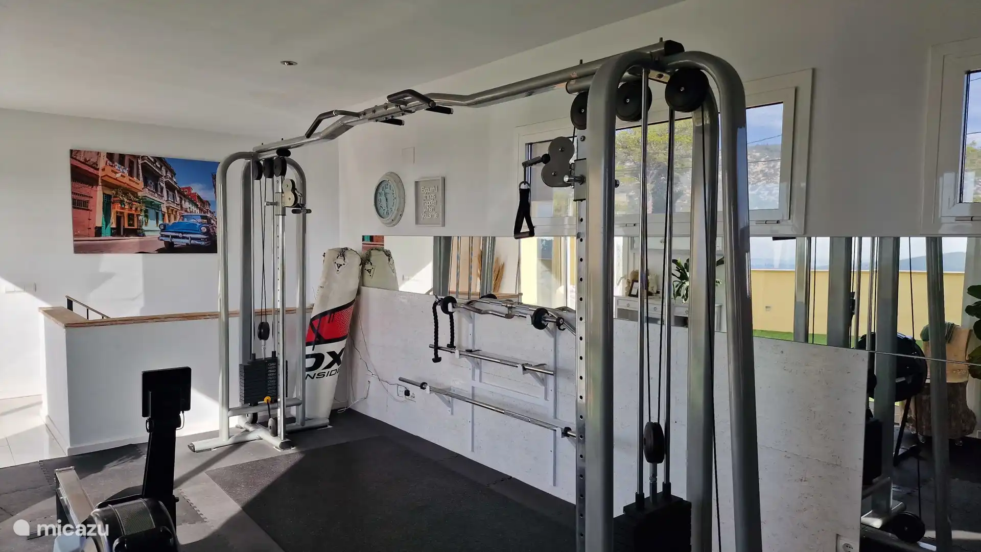 Goed uitgeruste gym met cable crossover, punchzak, Concept roeimachine, fiets, yogamaterialen.