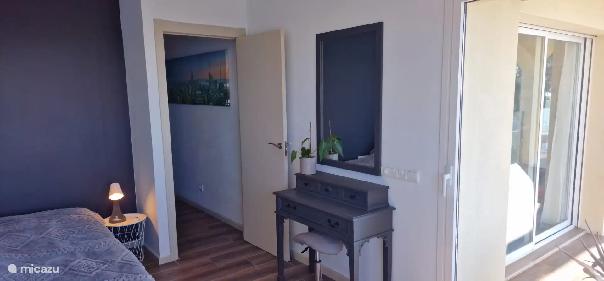 Slaapkamer met zicht op terras en halletje.