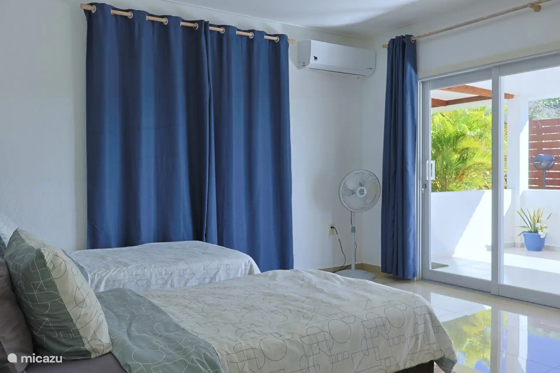 Slaapkamer met twee eenpersoons bedden, airconditioning, opbergruimte en openslaande deuren.
