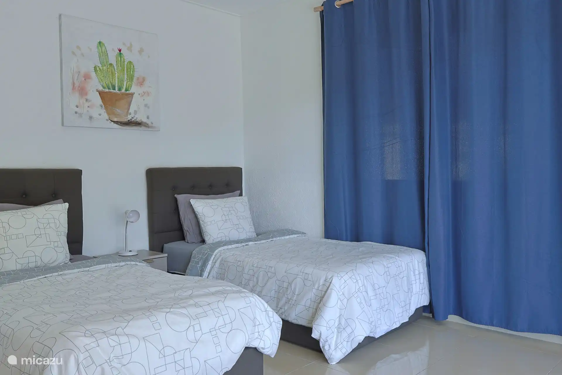 Slaapkamer met twee eenpersoons bedden, airconditioning, opbergruimte en openslaande deuren.