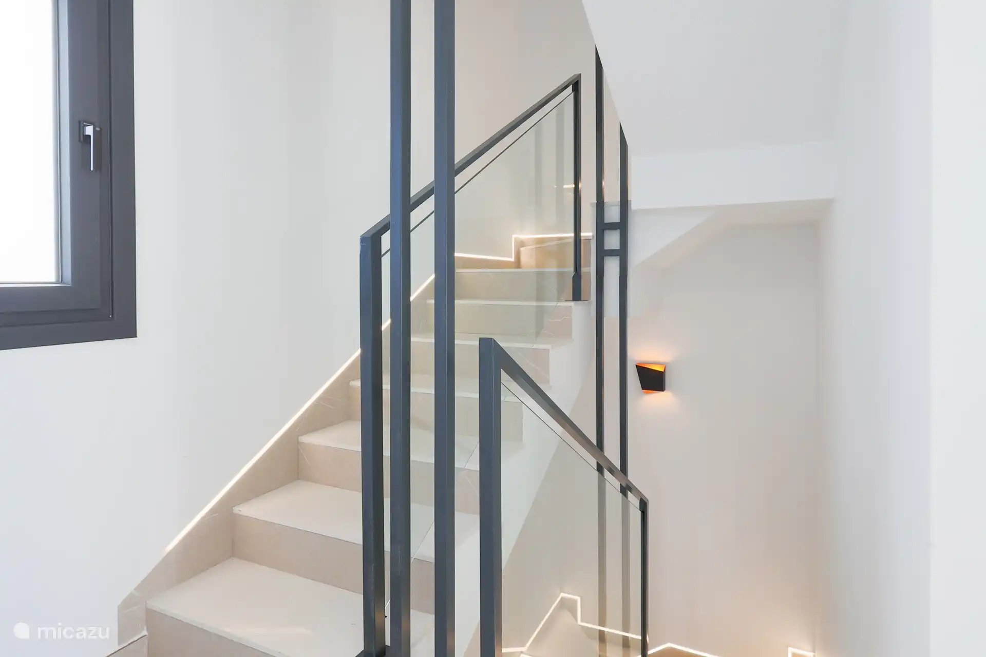 Entrada y escalera de lujo – Un impresionante salón moderno con una escalera elegante y atractiva iluminación LED integrada. Los acabados de alta calidad y la iluminación cálida dan a Villa Don Gr