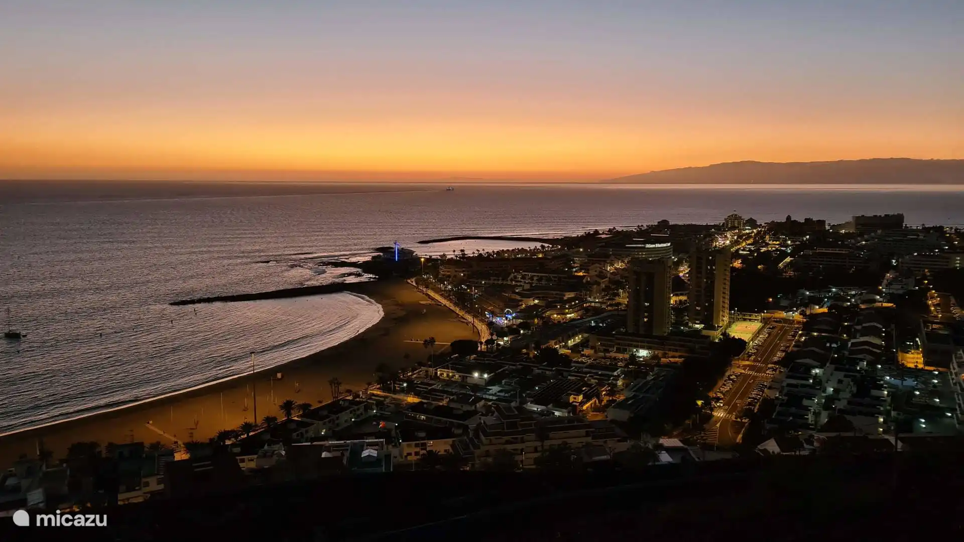 Prachtig uitzicht over Los Cristianos bij zonsondergang. De combinatie van zee, strand en verlichte stad zorgt voor een unieke en sfeervolle ervaring.