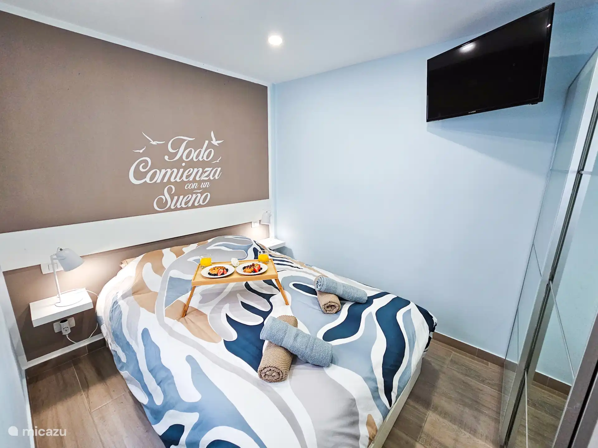 Knusse slaapkamer met een comfortabel tweepersoonsbed, sfeervolle nachtlampjes en verduisterende schermen voor optimale rust. Decoratieve muurdetails voegen een persoonlijk tintje toe.