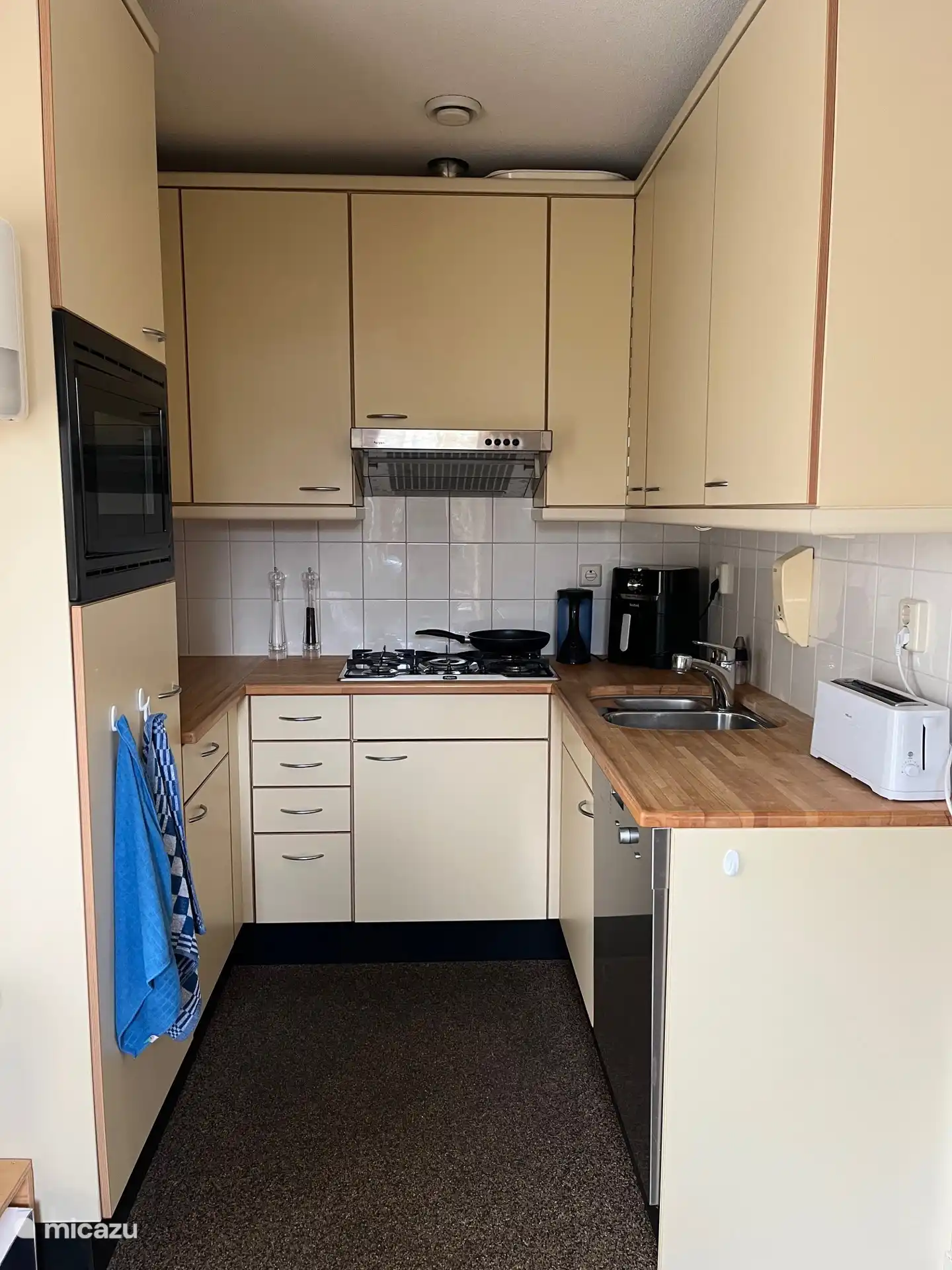 De kleine open keuken met koelkast, oven en vaatwasmachine