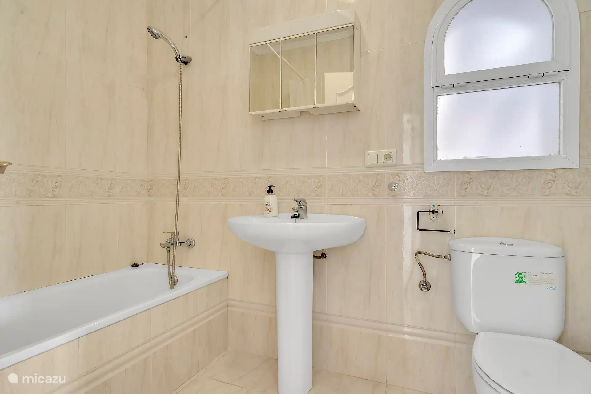 Badkamer met bad, toilet en wastafel.