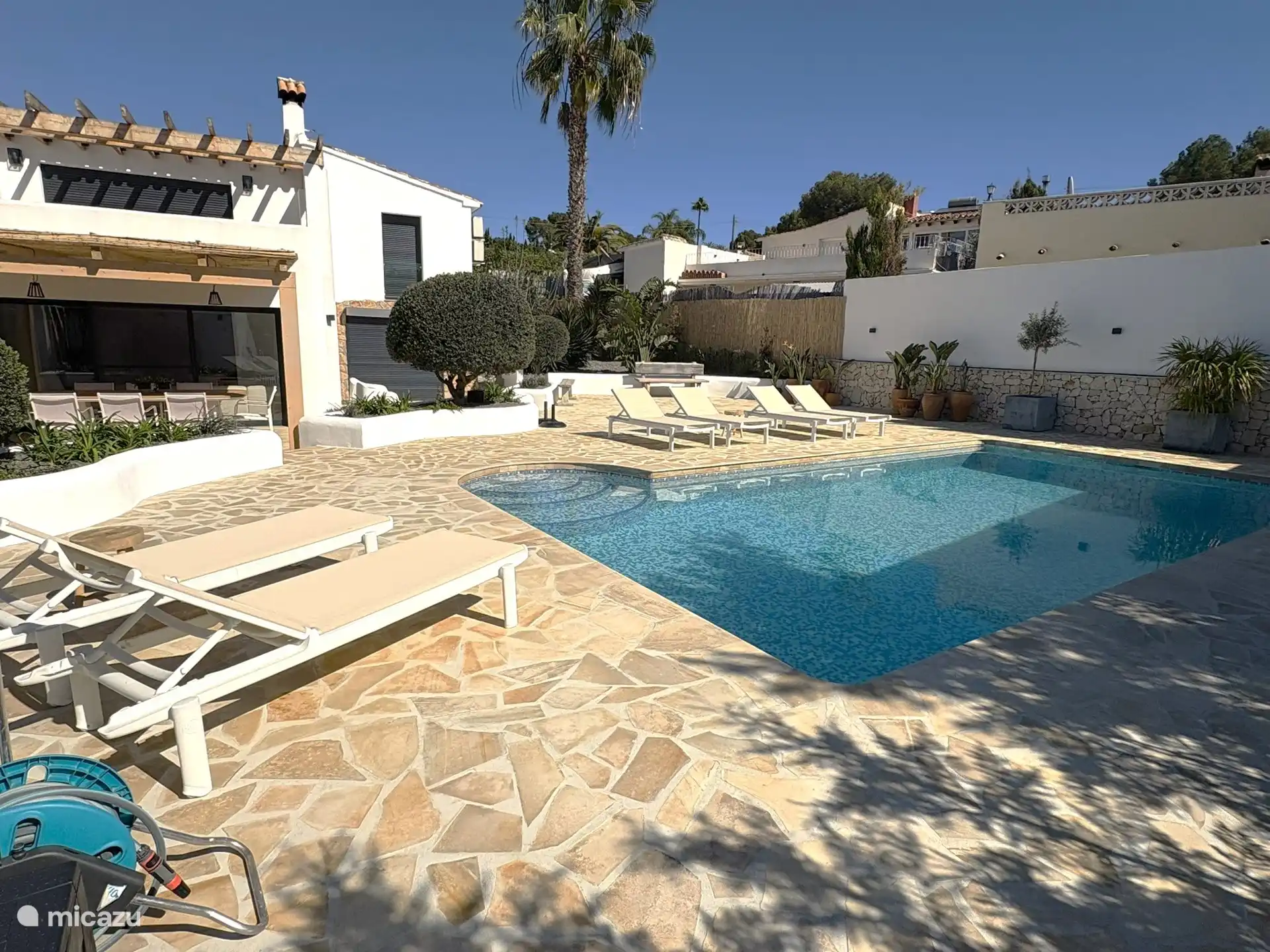 Groot privezwembad met ligbedden rondom op terras