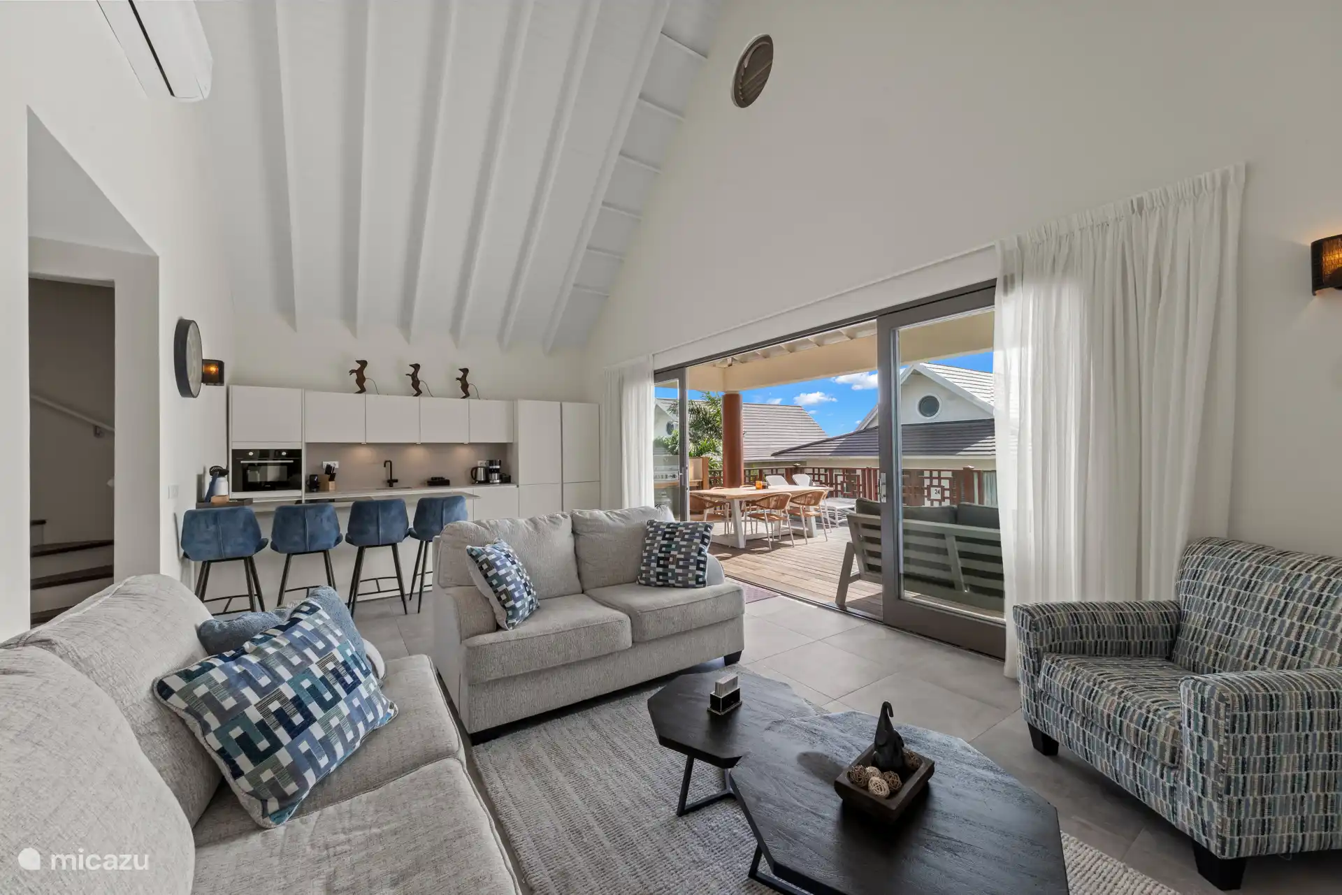 Grote schuifdeuren verbinden de woonkamer met het terras, waardoor het huis gevuld wordt met natuurlijk licht en een verkoelende bries.