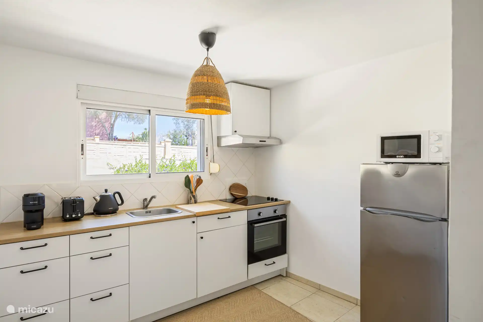 Die Küche der Wohnung mit Kühlschrank, Induktionsherd, Wasserkocher, Mikrowelle sowie komplettem Besteck und Geschirr.