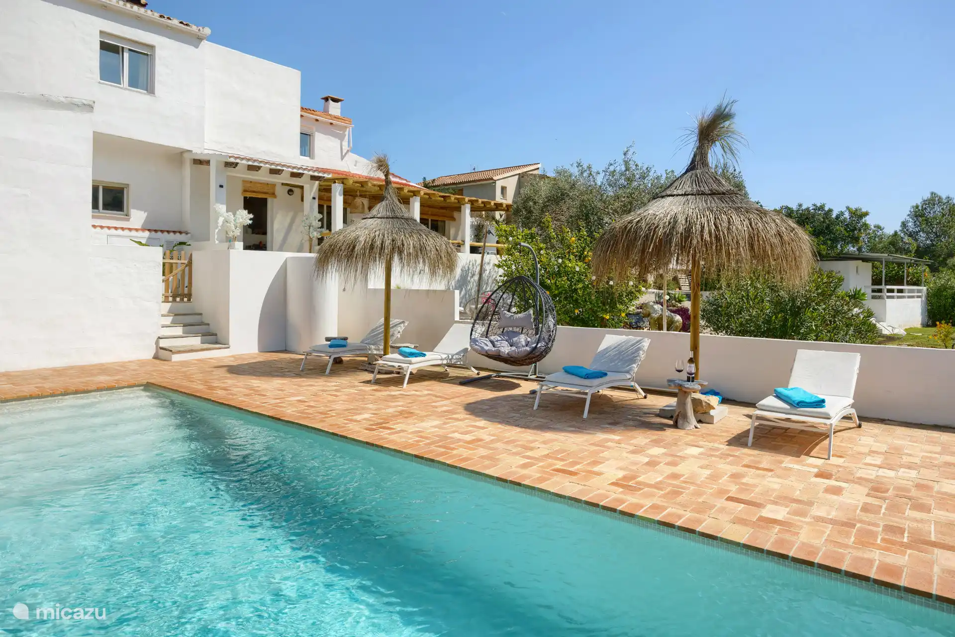 Schwimmbad mit 8 Sonnenbetten, 2 Stehschirmen und einem verschiebbaren Sonnenschirm.