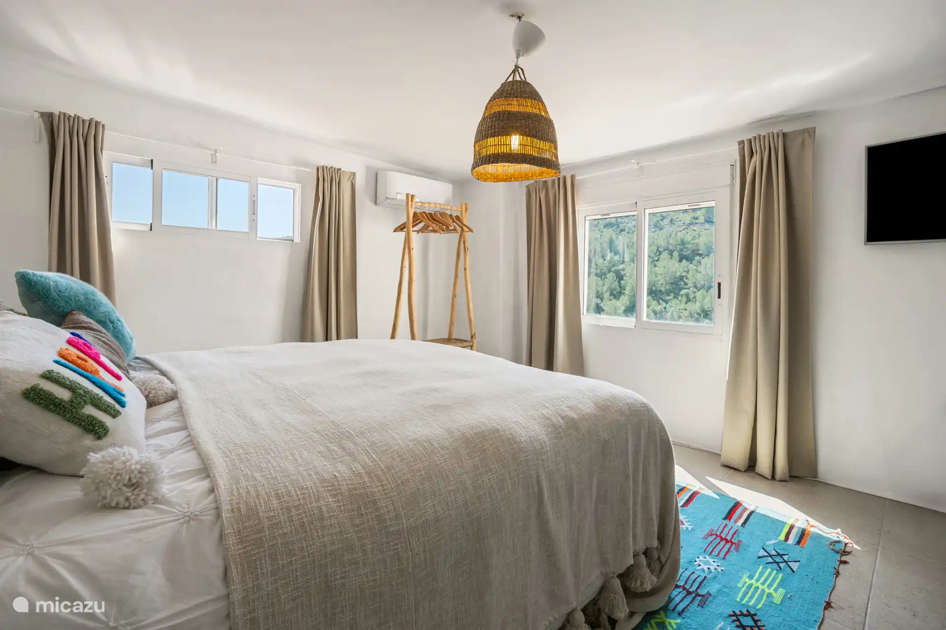 Oberes Schlafzimmer mit Doppelbett und Blick auf den Garten und den Wald