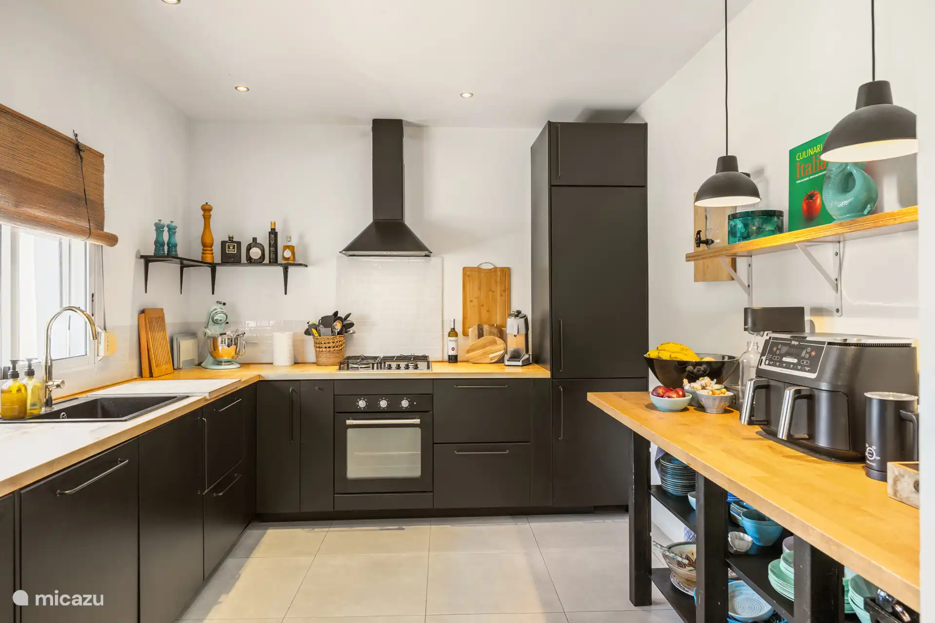 Die halboffene Küche mit allen Geräten und reichlich Besteck sowie verschiedenen Kochutensilien und Kräutern.