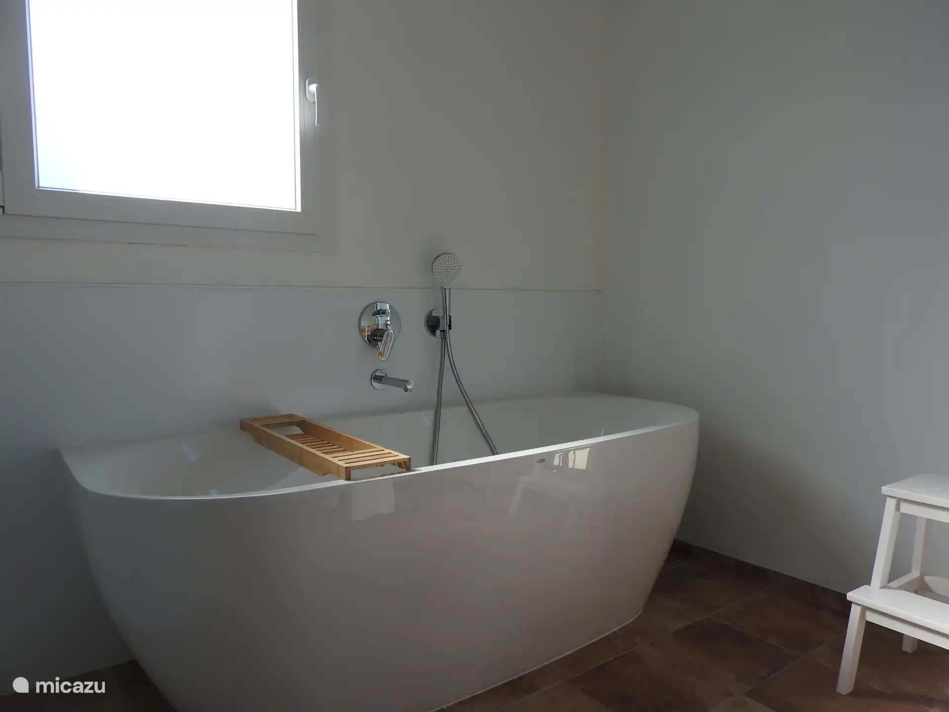 Badkamer met ligbad, open douche en dubbele wastafel. 