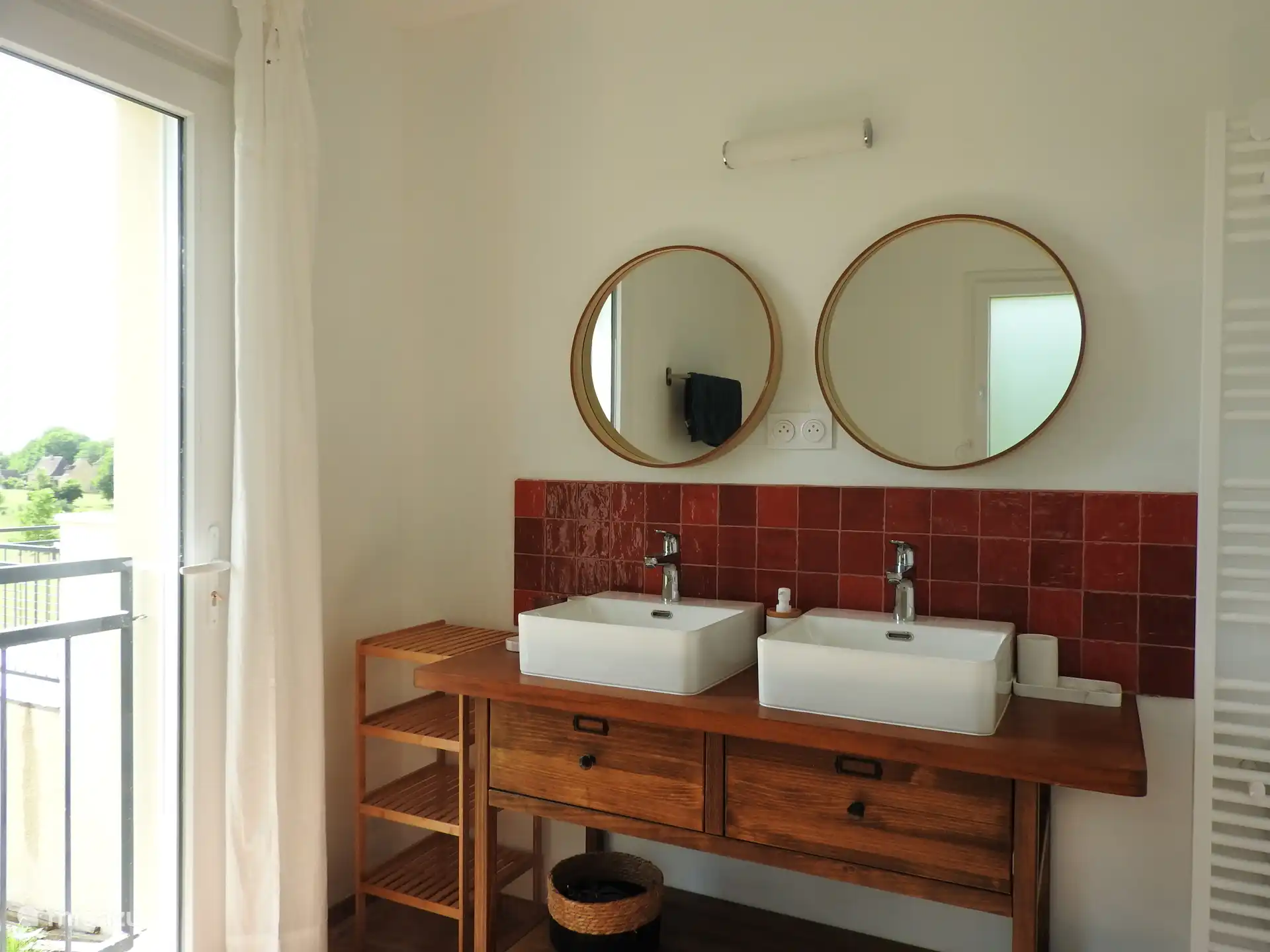 Badkamer met dubbele lavabo, bad en open douche met uitzicht