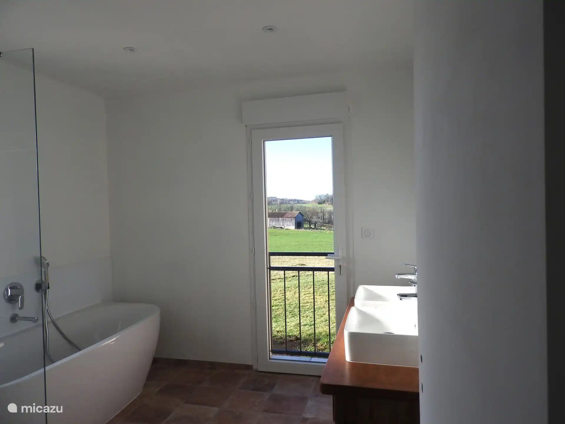 Badkamer met bad, open douche en dubbele wastafel