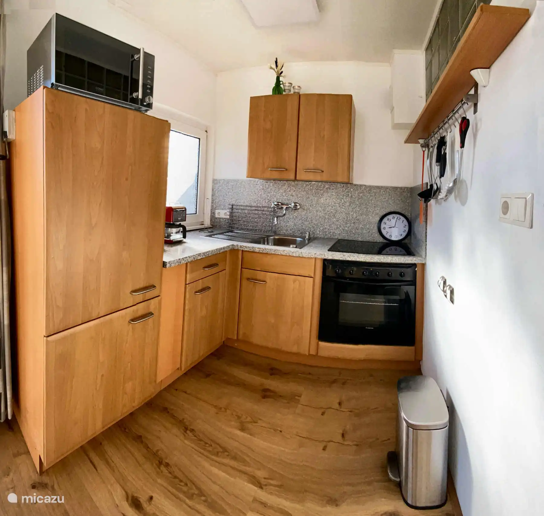 De keuken met grote koelkast, fornuis en oven