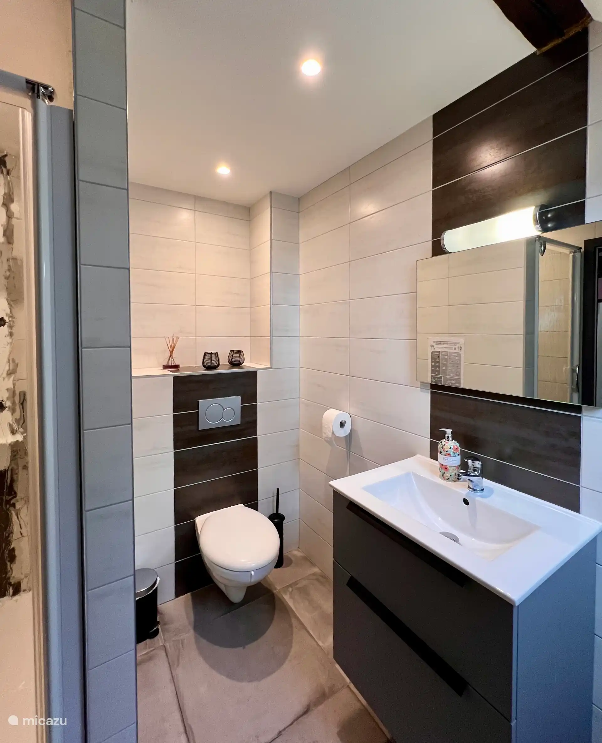 De badkamer heeft een straaldouche, een toilet, een wastafel en een wasmachine. 