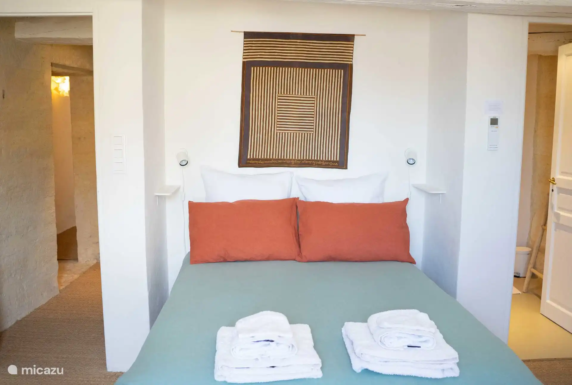 la cama en el dormitorio del entresuelo y su baño