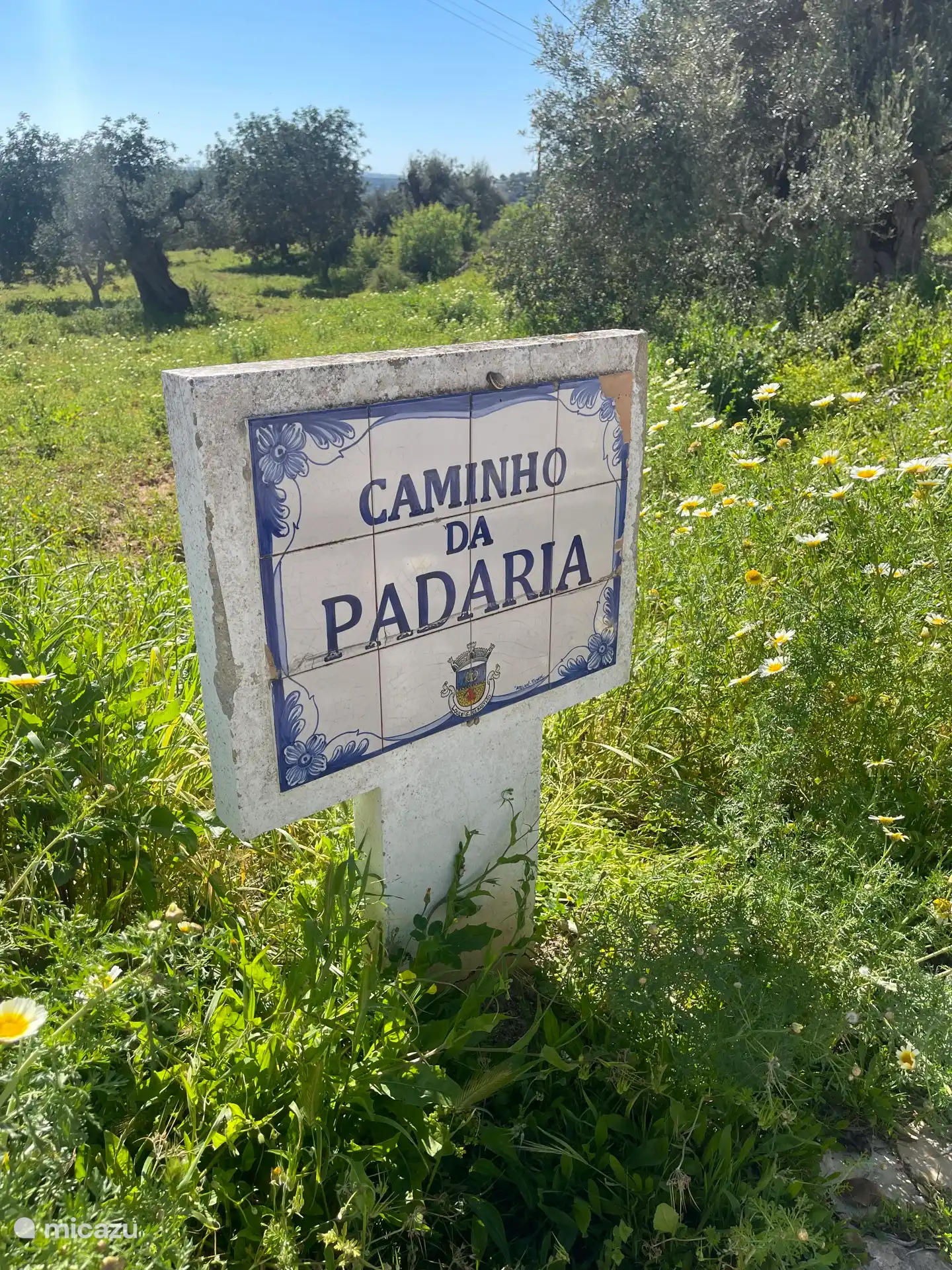 Nous avons choisi le nom de notre maison à cause du nom de la rue : Caminho da Padaria, « la route du boulanger » : Le boulanger passe deux fois par semaine, avec sa camionnette, tournoyant bruyamment. 