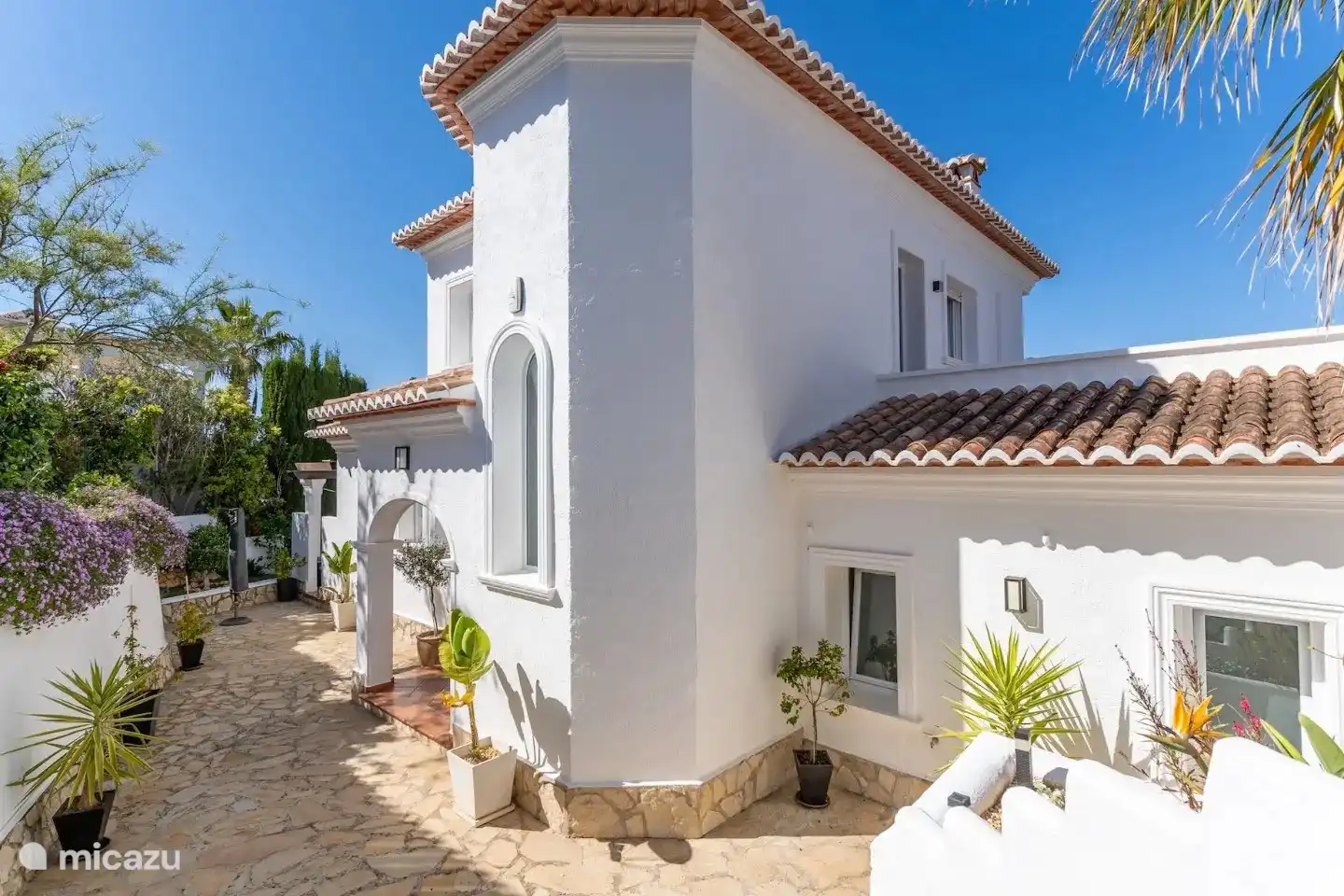 La entrada a la villa y algunos de los jardines establecidos y coloridos que rodean la villa.