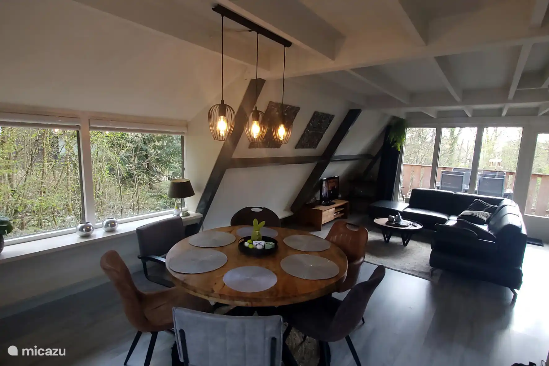 Salle à manger avec table ronde, 6 chaises et un coin salon.