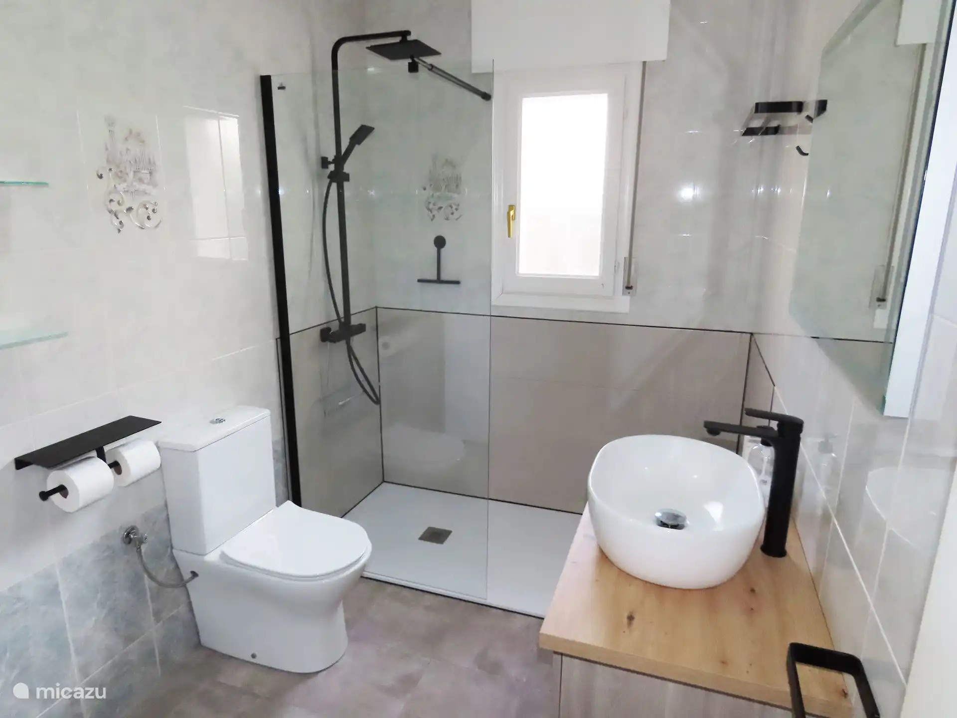 Badkamer met inloopdocuhe, toilet en wasmachine. 