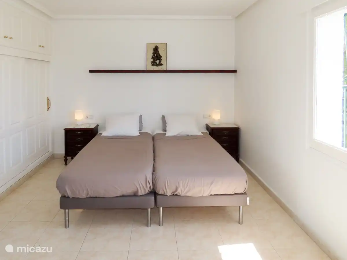 Slaapkamer met 2 enkele bedden en inbouw kledingkasten.