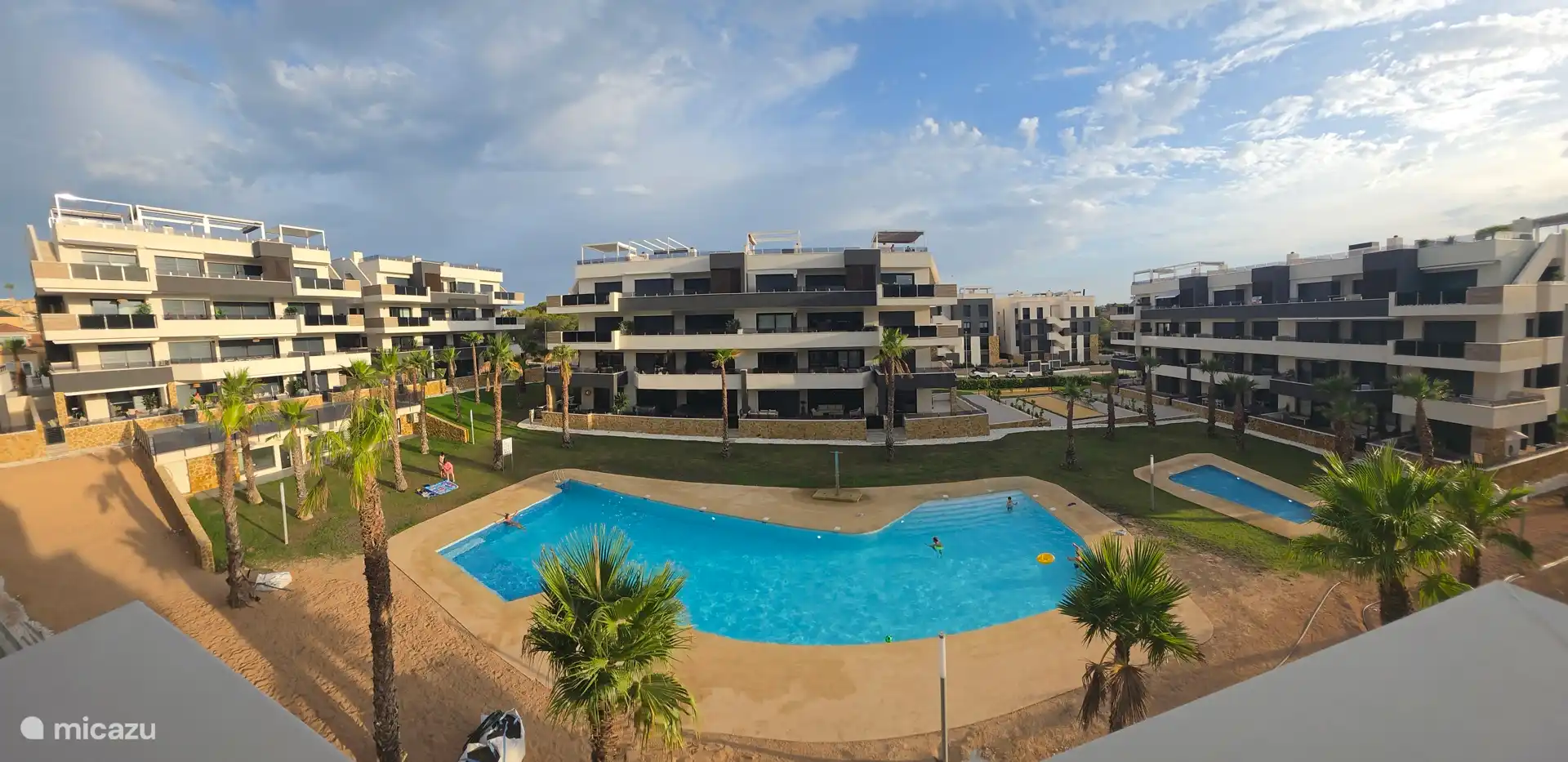 Jardín de palmeras con piscinas, pista de petangues y parque infantil